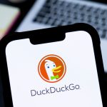 a DuckDuckGo logo is seen displayed on a smartphone